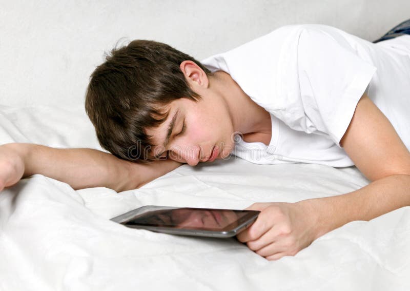 Tired Young Man Sleeps with Tablet Computer on the bed. Tired Young Man Sleeps with Tablet Computer on the bed