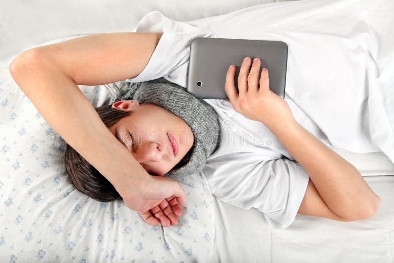 Tired Teenager sleeps with Tablet Computer on the Bed. Tired Teenager sleeps with Tablet Computer on the Bed