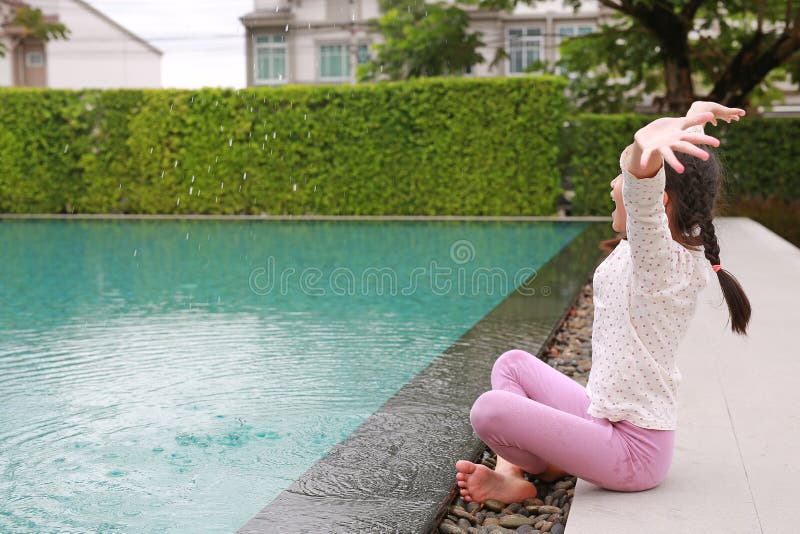 азиатская девочка, веселая, играет в воду у бассейна стоковые изображения