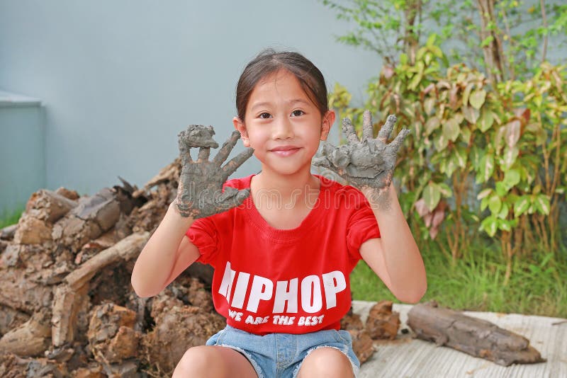 азиатская девочка играет с глина, показывая грязные руки стоковое изображение