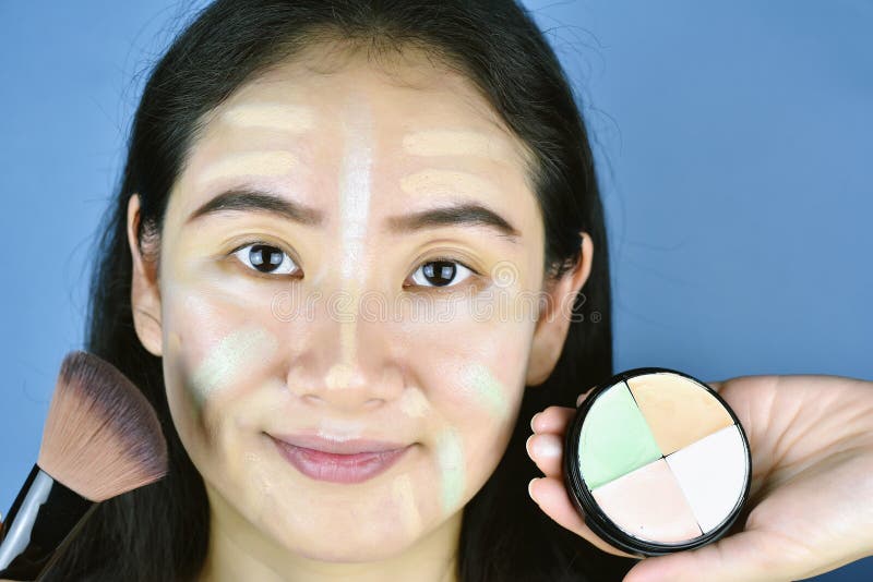 Азиатская женщина прикладывая учреждение макияжа косметик и используя concealer коррекции цвета стоковое изображение Азиатская женщина прикладывая учреждение макияжа косметик и используя concealer коррекции цвета стоковое изображение