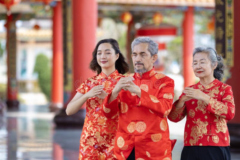 азиатская семья со старшими родителями в красном платье cheongsam qipao предлагает дань уважения богу предков внутри китайского бу стоковые изображения