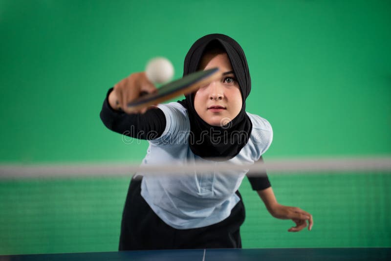 Asian Muslim female athlete hits the ball back while playing ping pong. Asian Muslim female athlete hits the ball back while playing ping pong