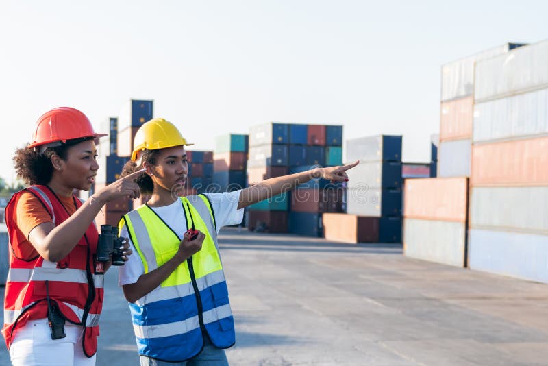 2 African American workers woman, Using a communication radio and binoculars, are working in containers industry, logistic transport Import-Export Cargo, to business shipping and warehouse concept. 2 African American workers woman, Using a communication radio and binoculars, are working in containers industry, logistic transport Import-Export Cargo, to business shipping and warehouse concept