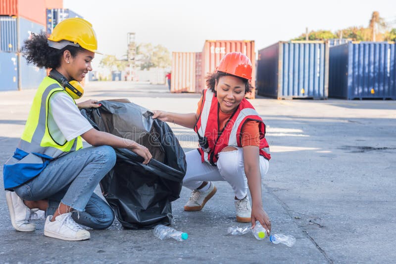 2 African American workers women are helping to clean the workplace in containers industry, collecting water bottles and rubbish in bags. 2 African American workers women are helping to clean the workplace in containers industry, collecting water bottles and rubbish in bags