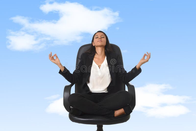 Американская бизнес-леди сидя на стуле офиса в йоге и раздумье позиции лотоса практикуя