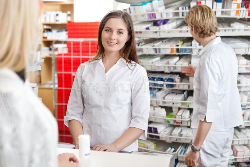 Pharmacist smiling while attending customer at counter. Pharmacist smiling while attending customer at counter