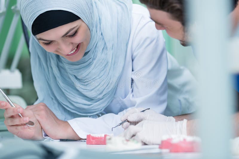 Арабские студенты с Hijab пока работающ на Denture ложных зубах