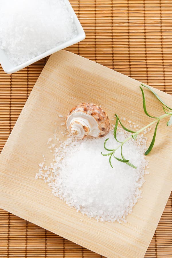 Overhead view of sea salt bath scrub arranged on a bamboo background with rosemary and a seashell. Overhead view of sea salt bath scrub arranged on a bamboo background with rosemary and a seashell.