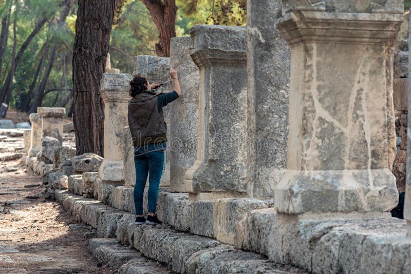 Phaselis, Turkey - November 08, 2021: archaeologist restores an ancient inscription on a column. Phaselis, Turkey - November 08, 2021: archaeologist restores an ancient inscription on a column