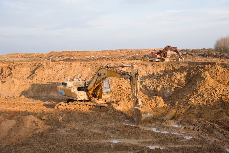 Археологи, работающие на openpit горнодобывающей промышленности. Экскаватор во время earthworks на карьере песка. Earthmoving тяже стоковые изображения