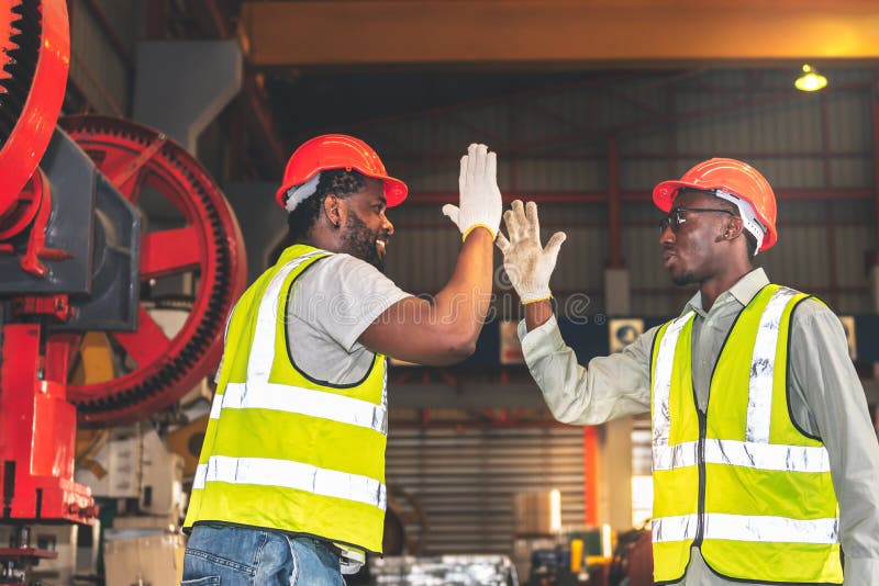 2 male worker African American, working in a factory, Shaking hands and happy that the work done together is successful, concept to teamwork of workers in industrial factories. 2 male worker African American, working in a factory, Shaking hands and happy that the work done together is successful, concept to teamwork of workers in industrial factories