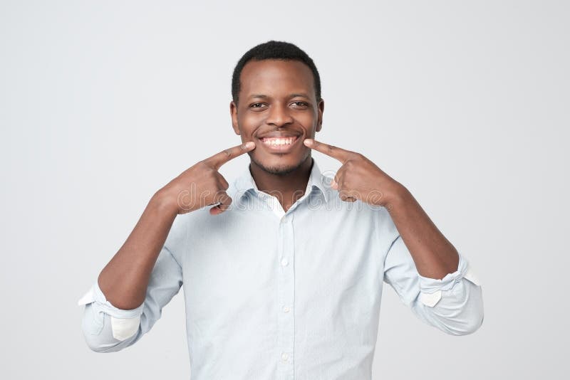 African young handsome man showing his excellent white teeth. Whitening dental care. African young handsome man showing his excellent white teeth. Whitening dental care.