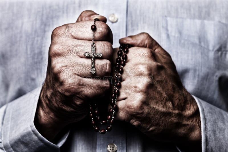 African American male hands praying holding a beads rosary with Jesus Christ in the cross or Crucifix on black background. Mature Afro American man with Christian Catholic religious faith. African American male hands praying holding a beads rosary with Jesus Christ in the cross or Crucifix on black background. Mature Afro American man with Christian Catholic religious faith