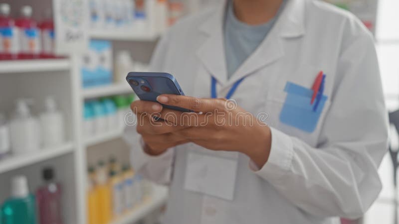Афроамериканка, фармацевт, пользуется смартфоном в аптеке стоковое фото rf