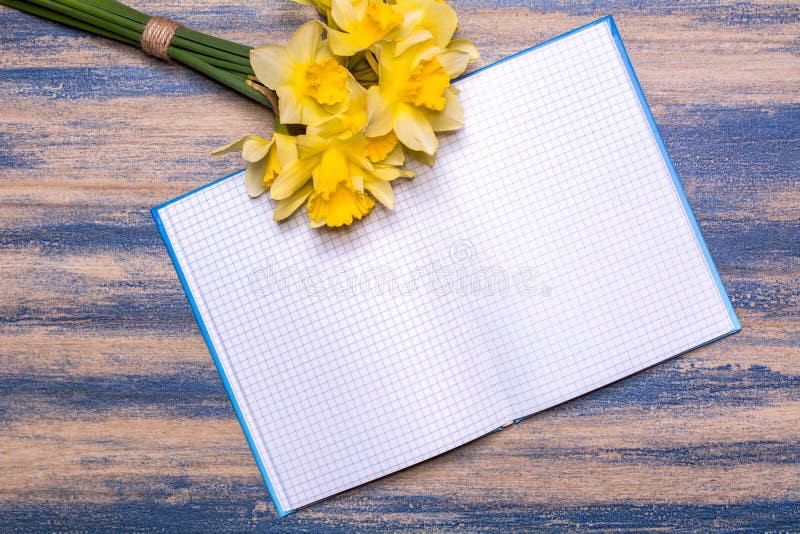 Блокнот на деревянной доске Желтые цветки daffodils на деревянном столе стоковые изображения Блокнот на деревянной доске Желтые цветки daffodils на деревянном столе стоковые изображения
