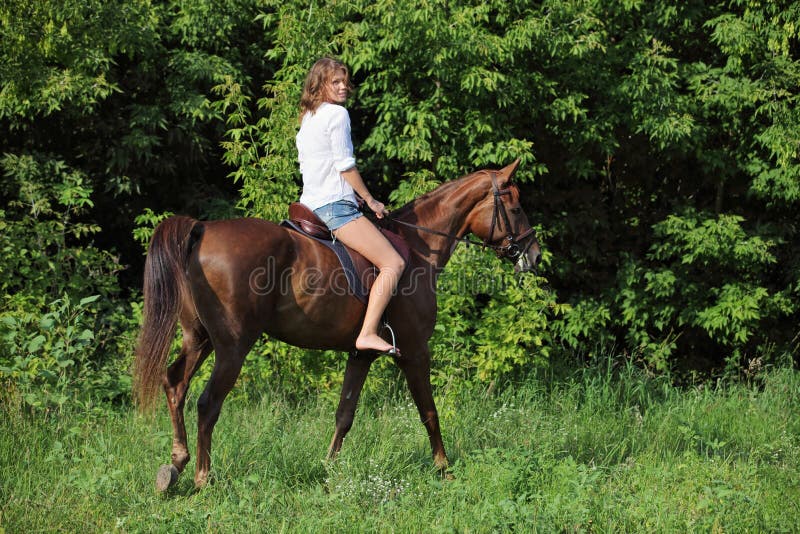 Beauty equestrian model rides a horse through a forest