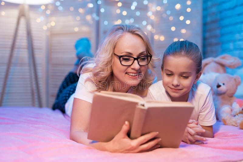 Бабушка и внучка книга чтения перед сном на ноче дома стоковое изображение rf Бабушка и внучка книга чтения перед сном на ноче дома стоковое изображение rf