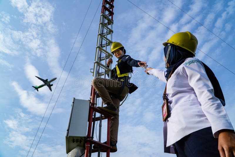 Badung, Bali, Dec 8th 2020: In a clearly day, 2 female technical workers repairing communication equipment at the airport. One of them is wearing a hijab. Badung, Bali, Dec 8th 2020: In a clearly day, 2 female technical workers repairing communication equipment at the airport. One of them is wearing a hijab