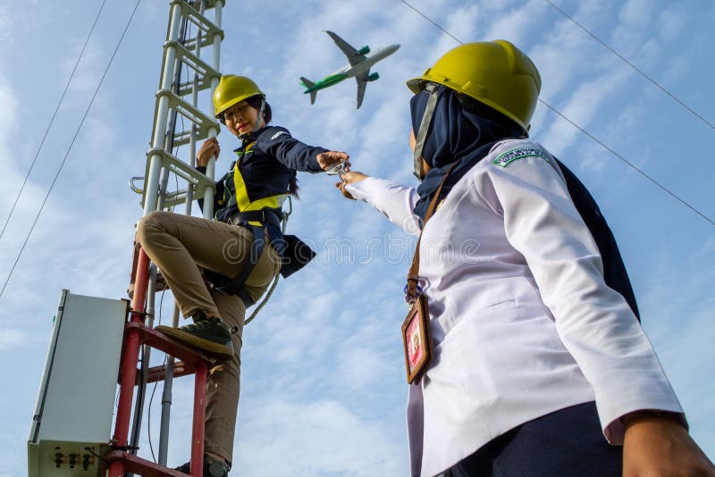 Badung, Bali, Dec 8th 2020: In a clearly day, 2 female technical workers repairing communication equipment at the airport. One of them is wearing a hijab. Badung, Bali, Dec 8th 2020: In a clearly day, 2 female technical workers repairing communication equipment at the airport. One of them is wearing a hijab