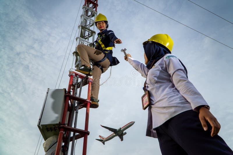 Badung, Bali, Dec 8th 2020: In a clearly day, 2 female technical workers repairing communication equipment at the airport. One of them is wearing a hijab. Badung, Bali, Dec 8th 2020: In a clearly day, 2 female technical workers repairing communication equipment at the airport. One of them is wearing a hijab