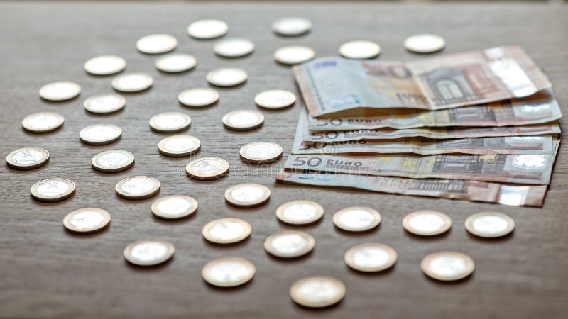 50 банкнот евро и монетки 1 евро на светлой деревянной предпосылке стоковое изображение rf 50 банкнот евро и монетки 1 евро на светлой деревянной предпосылке стоковое изображение rf
