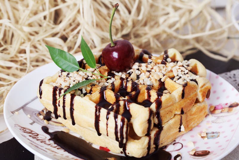 Бельгийские waffles с соусом и вишнями шоколада арахиса на плите стоковое фото Бельгийские waffles с соусом и вишнями шоколада арахиса на плите стоковое фото