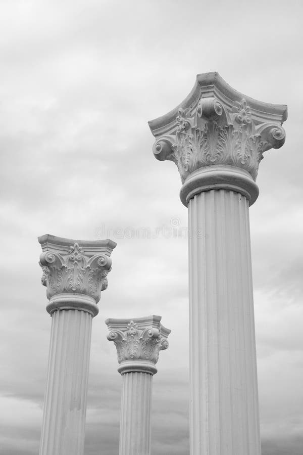 White columns in Greek style are looking in cloudy sky. White columns in Greek style are looking in cloudy sky