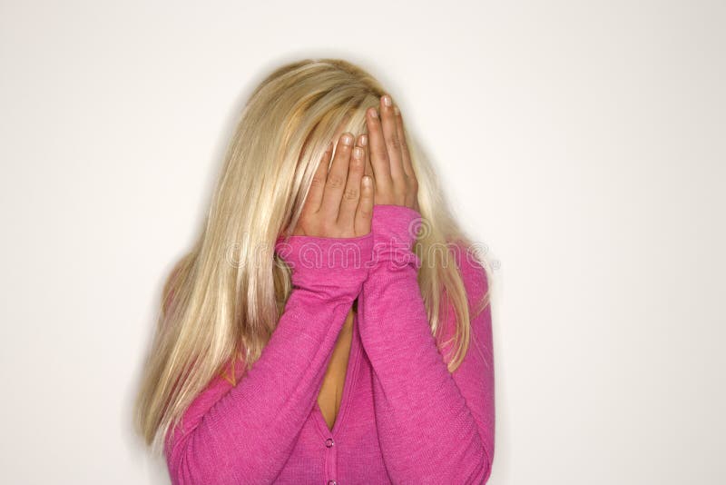 Portrait of attractive blonde Caucasian young adult woman wearing fuchsia covering face with hands. Portrait of attractive blonde Caucasian young adult woman wearing fuchsia covering face with hands.