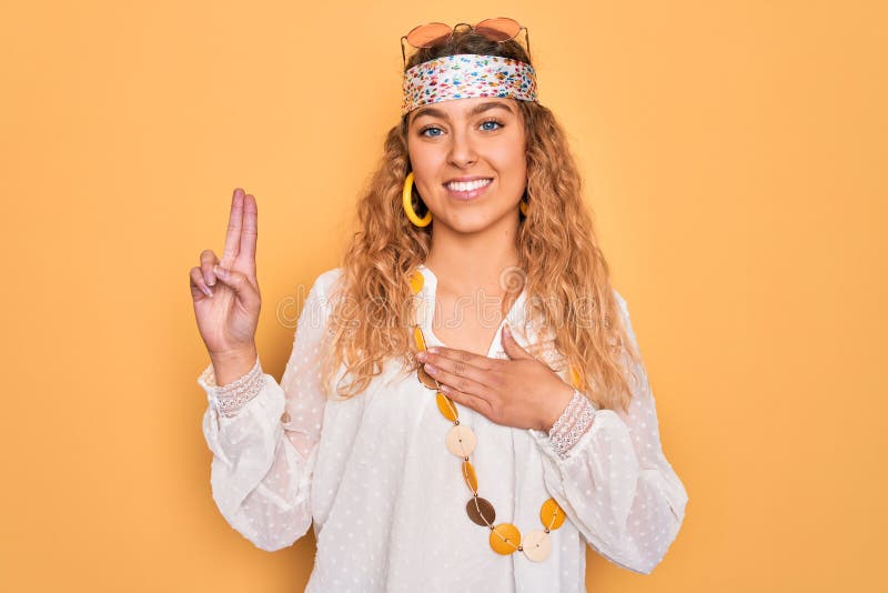 Young beautiful blonde hippie woman with blue eyes wearing sunglasses and accessories smiling swearing with hand on chest and fingers up, making a loyalty promise oath. Young beautiful blonde hippie woman with blue eyes wearing sunglasses and accessories smiling swearing with hand on chest and fingers up, making a loyalty promise oath
