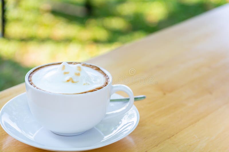 Белый latte чашки кофе с милой пеной молока искусства latte формы кота на деревянной таблице стоковые изображения Белый latte чашки кофе с милой пеной молока искусства latte формы кота на деревянной таблице стоковые изображения
