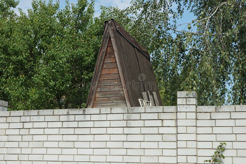 белый кирпичный забор на улице перед коричневым деревянным лофтом стоковое изображение