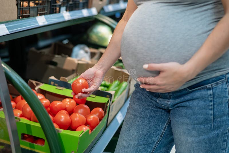 Pregnant woman buys tomatoes in the store. Pregnant woman buys tomatoes in the store