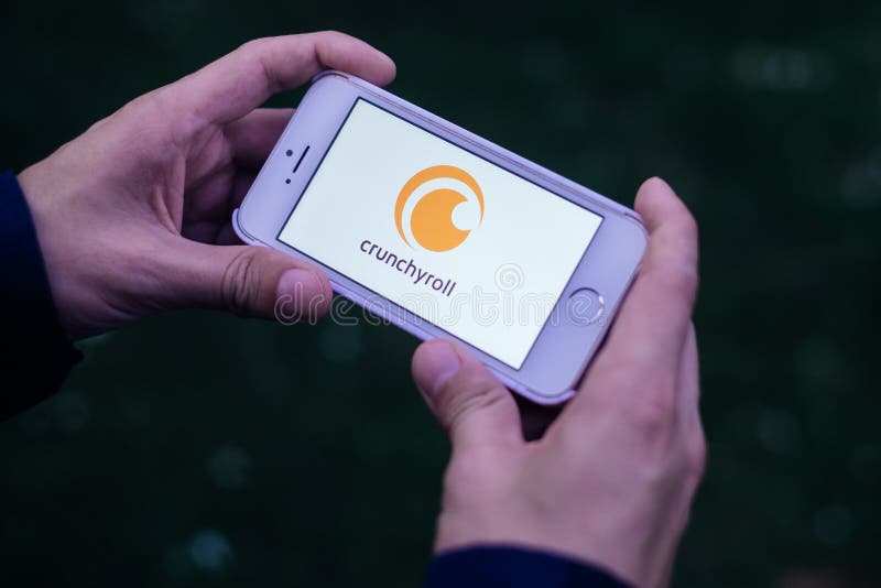БЕРЛИН, ГЕРМАНИЯ - 30-ОЕ МАЯ 2018: Крупный план рук держа экран iPhone с белым ЛОГОТИПОМ и ЗНАЧКОМ CRUNCHYROLL APP стоковое фото rf БЕРЛИН, ГЕРМАНИЯ - 30-ОЕ МАЯ 2018: Крупный план рук держа экран iPhone с белым ЛОГОТИПОМ и ЗНАЧКОМ CRUNCHYROLL APP стоковое фото rf