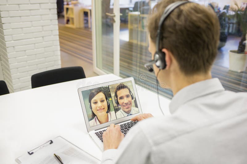 Бизнесмен в офисе на видеоконференции с шлемофоном, Skype стоковые фото Бизнесмен в офисе на видеоконференции с шлемофоном, Skype стоковые фото