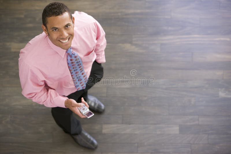 Businessman at work indoors smiling using cell phone. Businessman at work indoors smiling using cell phone