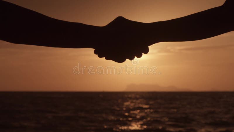 бизнесмен и женщина пожимают руки на фоне оранжевого заката. закрытие предприятия - мужчины и женщины