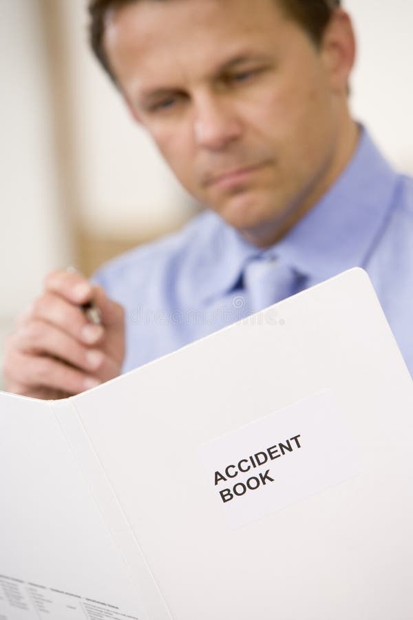 Close up of businessman indoors looking at Accident Book. Close up of businessman indoors looking at Accident Book