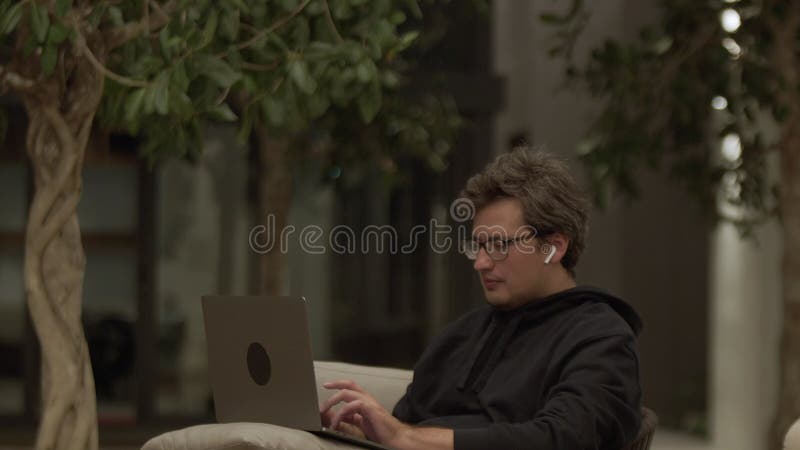 бизнесмен печатает в ноутбуке улыбаясь сидя в уютной гостиной