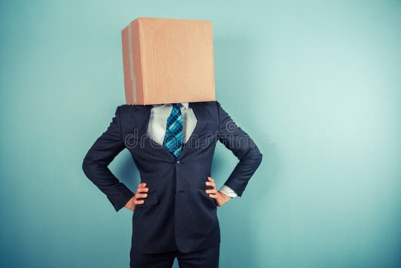 A businessman is standing with a cardboard box on his head. A businessman is standing with a cardboard box on his head