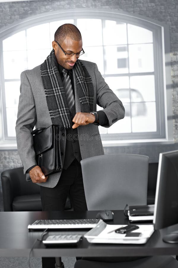 Бизнесмен смотрит на часы в офисе стоковое изображение