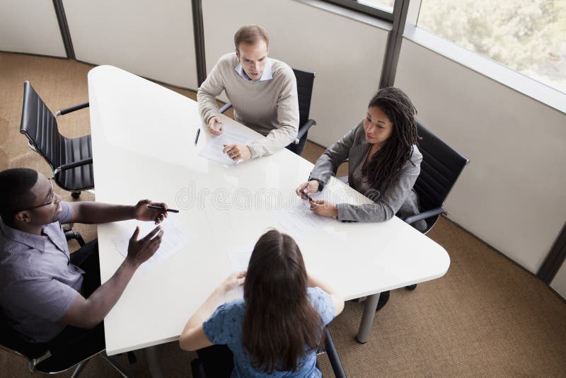 Four business people sitting at a conference table and discussing during a business meeting. Four business people sitting at a conference table and discussing during a business meeting