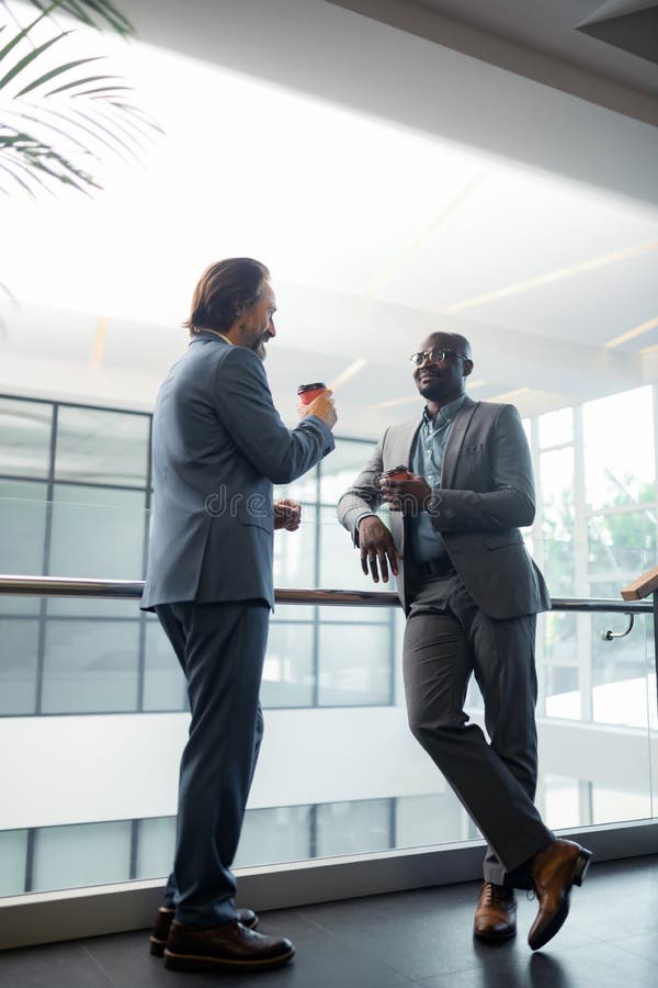 Бизнесмены чувствуя отдохнутый пока наслаждающся перерывом на чашку кофе в офисе стоковые фото