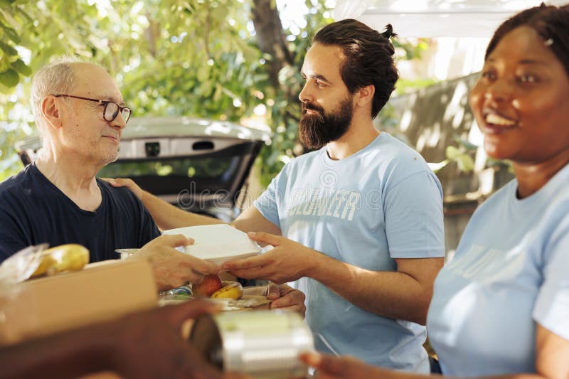 Close-up of multiethnic volunteers, including a smiling woman, distribute donations of food to the needy, offering help and hope to homeless people. Caring charity workers aiding the less privileged. Close-up of multiethnic volunteers, including a smiling woman, distribute donations of food to the needy, offering help and hope to homeless people. Caring charity workers aiding the less privileged.