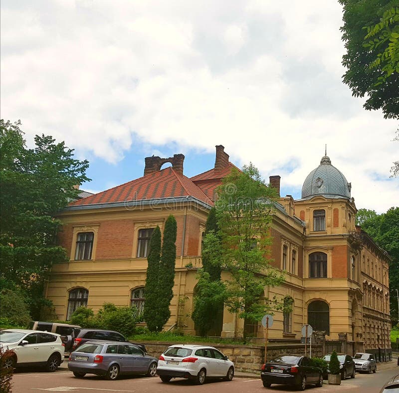 Благоустраивайте дом, кирпичное здание с красной крышей и купол Вокруг много автомобилей и деревьев вырастите Небо в облаках стоковые изображения Благоустраивайте дом, кирпичное здание с красной крышей и купол Вокруг много автомобилей и деревьев вырастите Небо в облаках стоковые изображения