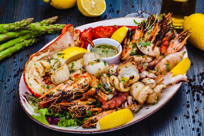 Блюда из морепродуктов. Жареные креветки, омар scallops кальмар осьминогов лангустов на белой тарелке стоковая фотография