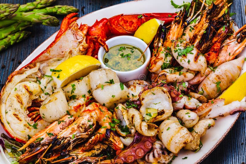 Блюда из морепродуктов. Жареные креветки, омар scallops кальмар осьминогов лангустов на белой тарелке стоковые изображения rf