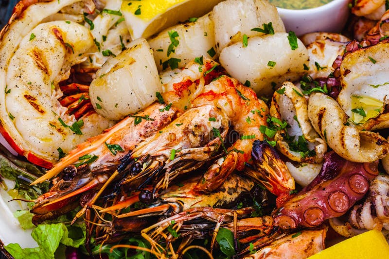 Блюда из морепродуктов. Жареные креветки, омар scallops кальмар осьминогов лангустов на белой тарелке стоковые изображения rf