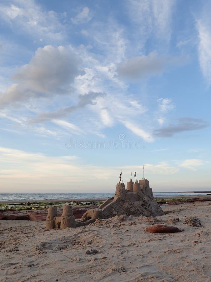 Большой sandcastle на насыпи с ровом, & пасмурное голубое небо стоковые изображения Большой sandcastle на насыпи с ровом, & пасмурное голубое небо стоковые изображения