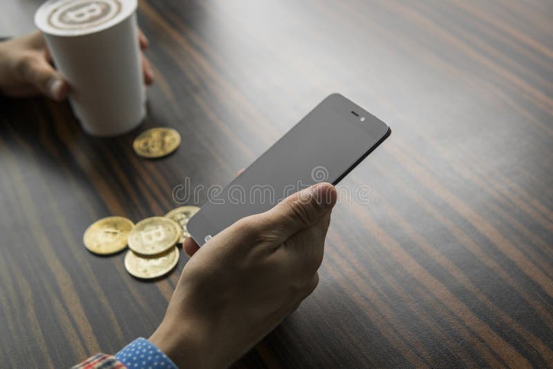 Богатый человек держа монетку bitcoin и выпивая кофе с телефоном и золотые монеты bitcoin на таблице Выгода от стоковое фото Богатый человек держа монетку bitcoin и выпивая кофе с телефоном и золотые монеты bitcoin на таблице Выгода от стоковое фото